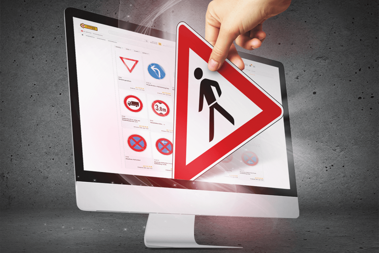 Monitor der den Webshop der Schilderwerke-Beutha zeigt und eine Hand ,die gerade ein Verkehrsschild durch den Monitor heraus holt