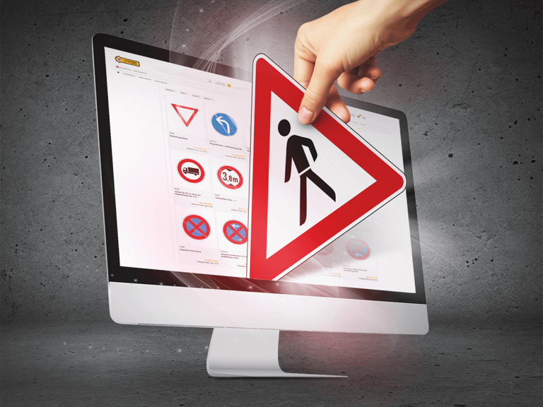 Monitor der den Webshop der Schilderwerke-Beutha zeigt und eine Hand ,die gerade ein Verkehrsschild durch den Monitor heraus holt