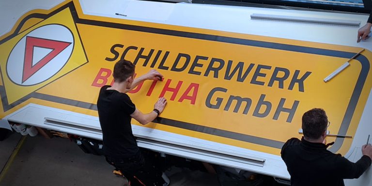 Werbetechniker Schilderwerk Beutha die gerade eine Folie bearbeiten