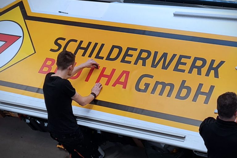 Werbetechniker Schilderwerk Beutha die gerade eine Folie bearbeiten