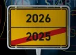 Symbolbild Jahreswechsel 2025 zu 2026, Ortsschild mit durchgestrichenem Jahr 2025 und neuem Jahr 2026