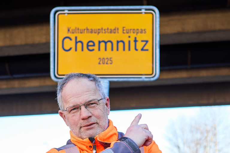 Ein Monteur des Schilderwerk Beutha vor einer Ortstafel der Stadt Chemnitz auf der Neefestraße.