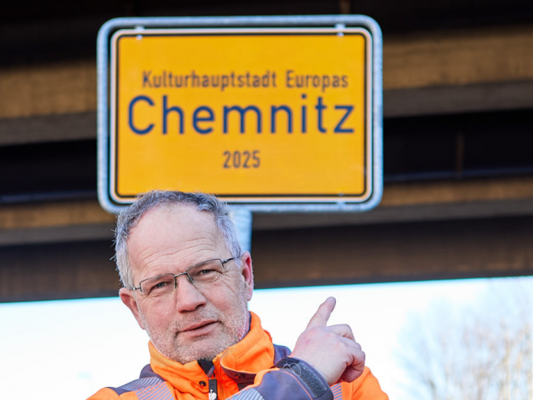 Ein Monteur des Schilderwerk Beutha vor einer Ortstafel der Stadt Chemnitz auf der Neefestraße.