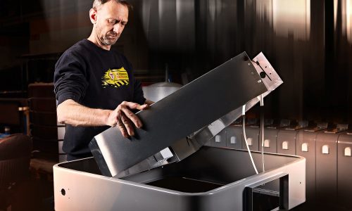 Foto eines Mitarbeiters des Schilderwerk Beutha, welcher ein Fußgängerüberwegtransparent montiert. Im Hintergrund sind weitere FGÜs zu sehen.