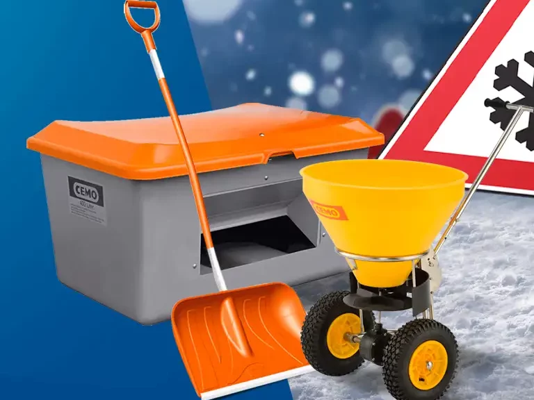 Grauer Streugutbehälter mit orangem Deckel, Schneeschaufel und gelbem Streuwagen vor Schneeflocken-Verkehrsschild