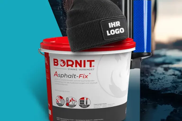 Eimer mit Asphalt-Reparaturmaterial steht auf einer nassen Asphaltfläche, darauf liegt eine schwarze Strickmütze
