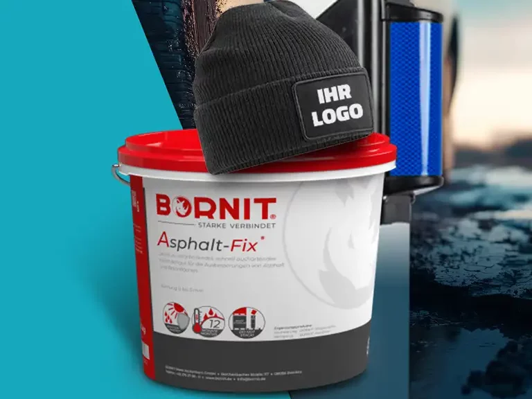 Eimer mit Asphalt-Reparaturmaterial steht auf einer nassen Asphaltfläche, darauf liegt eine schwarze Strickmütze