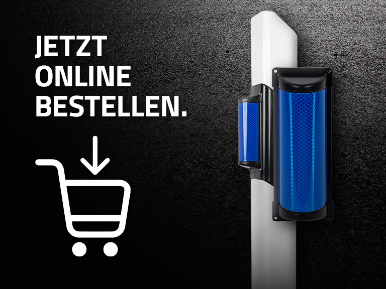 Blauer Wildwarnreflektor an einem weißen Pfosten, daneben der Text ‚Jetzt online bestellen.‘ und ein Einkaufswagen-Symbol