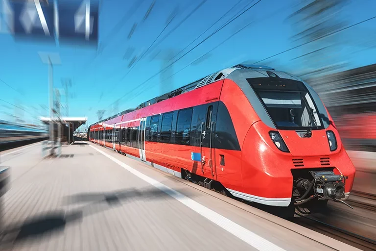 Moderner Regionalzug fährt mit hoher Geschwindigkeit in einen Bahnhof ein
