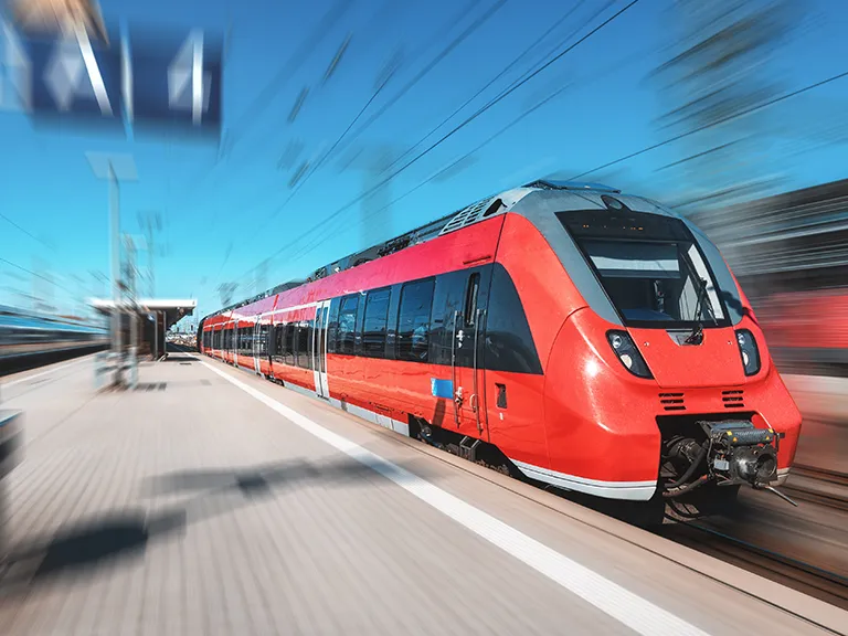 Moderner Regionalzug fährt mit hoher Geschwindigkeit in einen Bahnhof ein