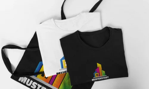 Schwarzes und weißes T-Shirt sowie Stofftasche mit farbigem Firmenlogo für Textildruck und Werbemittel.