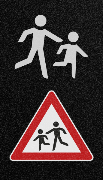 Verkehrszeichen "Achtung Kinder" als Bodenmarkierungen auf Asphaltboden.