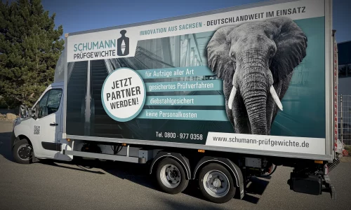 LKW-Kofferbeschriftung für Schumann Prüfgewichte mit großformatigem Elefantenmotiv, Unternehmenslogo und Leistungsbotschaften zur Aufzugsprüfung auf einem Anhängerfahrzeug. LKW-Kofferbeschriftung für Schumann Prüfgewichte mit großformatigem Elefantenmotiv, Unternehmenslogo und Leistungsbotschaften zur Aufzugsprüfung auf einem Anhängerfahrzeug.