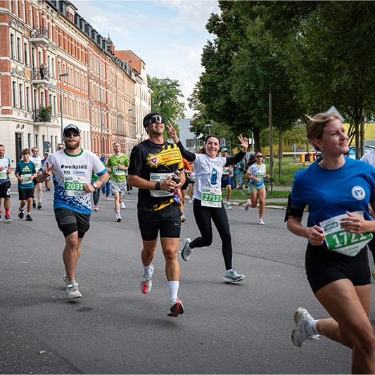 Läuferinnen und Läufer beim Firmenlauf Chemnitz 2026, darunter ein Teilnehmer des Schilderwerk Beutha im schwarz-gelben Teamshirt.