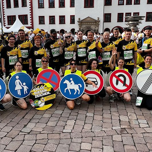 Team des Schilderwerk Beutha beim Firmenlauf Chemnitz 2026 mit verschiedenen Verkehrszeichen.