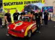 Sechs Teammitglieder von SW Design am Messestand der FLORIAN 2026 mit einem rot-gelben Feuerwehr-Trabant.