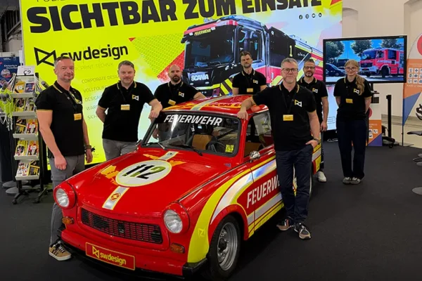 SW-Design-Team auf der FLORIAN 2026 in Dresden Sechs Teammitglieder von SW Design am Messestand der FLORIAN 2026 mit einem rot-gelben Feuerwehr-Trabant.